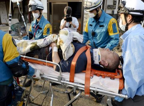 A man is carried away by a rescue workers after being rescued from his collapsed home caused by an earthquake in Mashiki town, Kumamoto prefecture, southern Japan, April 16, 2016. PHOTO BY REUTERS/Kyodo