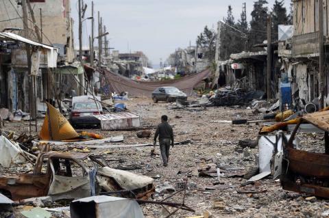 A man walks in a street with abandoned vehicles and and damaged buildings in the northern Syrian town of Kobani, January 30, 2015. PHOTO BY REUTERS/Osman Orsal