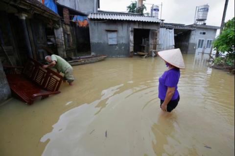 A man (L) cleans a chair at his submerged house after a heavy rain caused by a tropical depression in Hanoi, Vietnam, October 16, 2017. PHOTO BY REUTERS/Kham