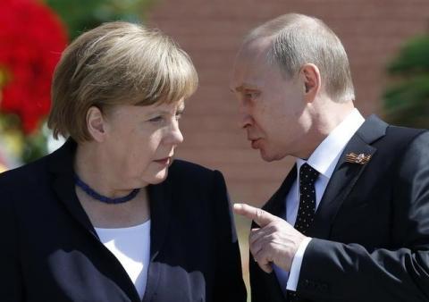 Russian President Vladimir Putin speaking with German Chancellor Angela Merkel at the Tomb of the Unknown Soldier by the Kremlin walls in Moscow, Russia, May 10, 2015. PHOTO BY REUTERS/Maxim Shemetov