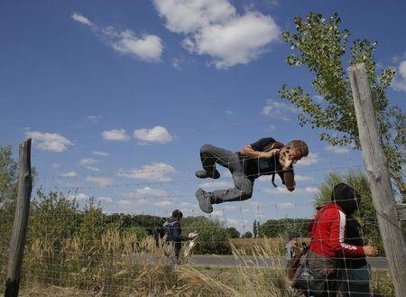 A migrant jumps over a road protection fence as they leave a collection point in the village of Roszke, Hungary, September 9, 2015. PHOTO BY REUTERS/Marko Djurica