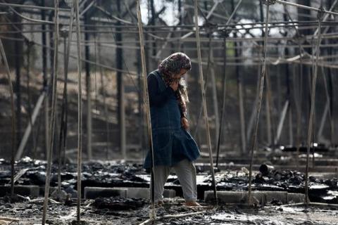 A migrant stands among the remains of a burned tent at the Moria migrant camp, after a fire that ripped through tents and destroyed containers during violence among residents, on the island of Lesbos, Greece, September 20, 2016. PHOTO BY REUTERS/Giorgos Moutafis