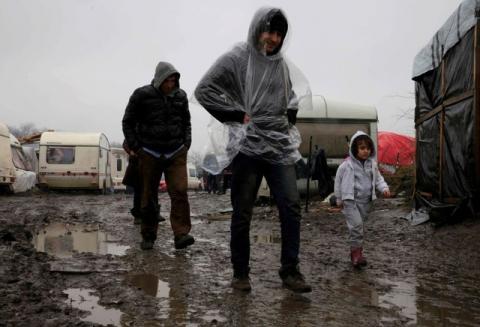 Migrants walk in the mud in the southern part of a camp for migrants called the "jungle", on a rainy winter day in Calais, northern France, February 22, 2016. PHOTO BY REUTERS/Pascal Rossignol