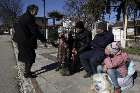 A local (L) offers migrants who are making their way to the Greek-Macedonian border something to eat, at the Greek village of Idomeni, Greece, March 5, 2016. PHOTO BY REUTERS/Alexandros Avramidis