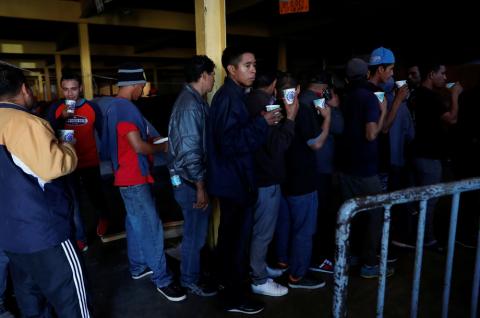 Migrants, part of a caravan of thousands from Central America trying to reach the United States, wait in line for food at their temporary shelter near the U.S. border in Tijuana, Mexico, December 18, 2018. PHOTO BY REUTERS/Leah Millis