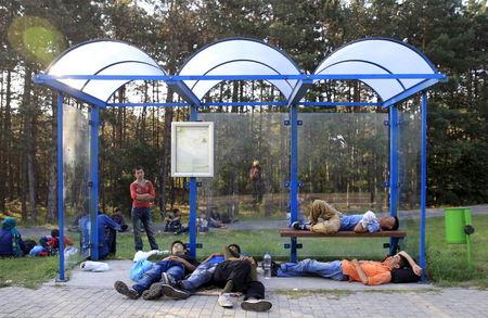 Migrants sleep at a bus stop after crossing into Hungary from the border with Serbia near Asotthalom, Hungary, August 30, 2015. PHOTO BY REUTERS/Bernadett Szabo