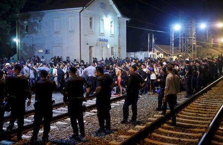 Croatian police stand guard in front of migrants at the train station in Tovarnik, Croatia, September 17, 2015. PHOTO BY REUTERS/Antonio Bronic