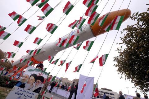 A boy holding a placard with pictures of (L-R) President Hassan Rouhani, the late founder of the Islamic Revolution Ayatollah Ruhollah Khomeini, and Iran's Supreme Leader Ayatollah Ali Khamenei, poses for camera in front of a model of Simorgh satellite-carrier rocket during a ceremony marking the 37th anniversary of the Islamic Revolution, in Tehran, February 11, 2016. PHOTO BY REUTERS/Raheb Homavandi/TIMA