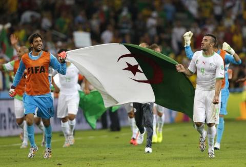 Algeria's goalkeeper Mohamed Lamine Zemmamouche (L) and Essaid Belkalem carry their national flag as they celebrates at the end of their 2014 World Cup Group H soccer match against Russia at the Baixada arena in Curitiba, June 26, 2014. PHOTO BY REUTERS/Maxim Shemetov