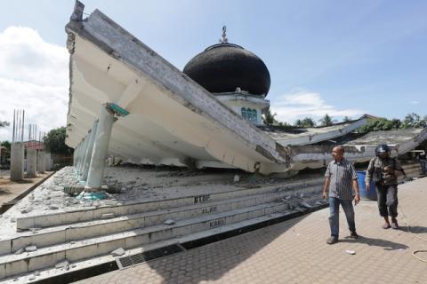 People walk near a collapsed mosque following an earthquake in Meuredu, Pidie Jaya in the northern province of Aceh, Indonesia, December 7, 2016. PHOTO BY REUTERS/Irwansyah Putra