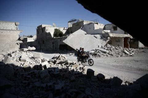 Men ride a motorcycle near damaged buildings in the rebel held Douma neighbourhood of Damascus, Syria, September 22, 2016. PHOTO BY REUTERS/Bassam Khabieh