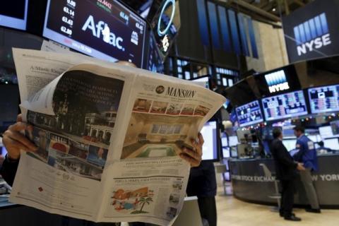 A trader reads the newspaper on the floor of the New York Stock Exchange, December 4, 2015. PHOTO BY REUTERS/Brendan McDermid