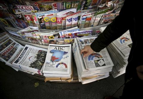 A man takes a newspaper at a kiosk in central Madrid, Spain, December 21, 2015. PHOTO BY REUTERS/Andrea Comas