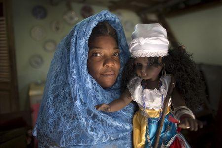 School teacher Niurka Mola, 50, holds a doll which symbolises the African sea goddess Yemaya before a ceremony in her home, a house known as Cabildo, or religious house by Santeria tradition, in downtown Havana, August 7, 2015. PHOTO BY REUTERS/Alexandre Meneghini