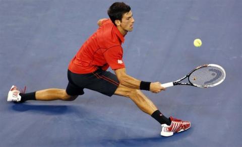 Novak Djokovic of Serbia runs down a forehand against Ricardas Berankis of Lithuania
