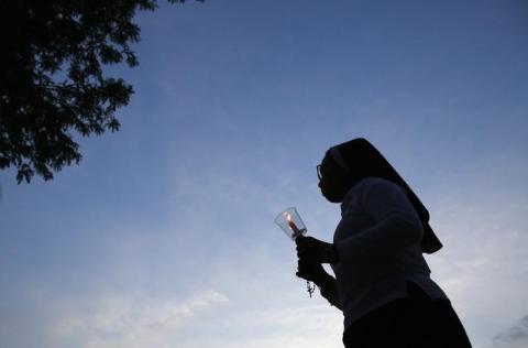 A nun walks to a candlelight vigil in Stone Park, Illinois, June 27, 2014. PHOTO BY REUTERS/Jim Young