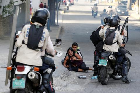 Opposition supporters affected by tear gas react next to members of the security forces during a rally against Venezuelan President Nicolas Maduro's government in Caracas. PHOTO BY REUTERS/Andres Martinez Casares