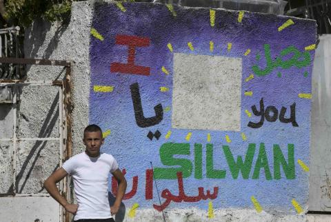 A Palestinian youth stands next to a wall painted with graffiti, outside a house which Jewish settlers moved into, in the east Jerusalem neighbourhood of Silwan September 30, 2014. PHOTO BY REUTERS/Baz Ratner