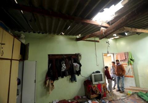 Palestinians look at the damage to a house, where medical officials said fragments from a missile fired by an Israeli aircraft killed a 10-year-old Palestinian boy, in the northern Gaza Strip, March 12, 2016. PHOTO BY REUTERS/Mohammed Salem