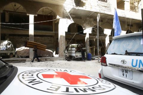 People carry their belonging next to International Red Cross (ICRC) and U.N aid convoys in the besieged town of Douma, Eastern Ghouta, in Damascus, Syria, March 9, 2018. PHOTO BY REUTERS/ Bassam Khabieh
