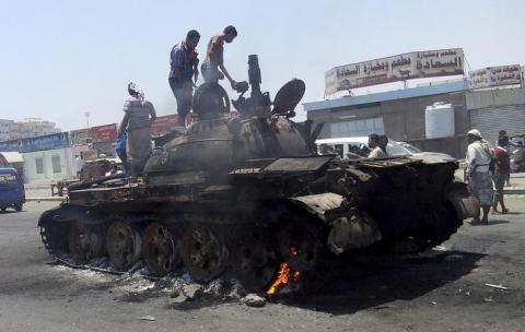 People stand on a tank that was burnt during clashes on a street in Yemen's southern port city of Aden, March 29, 2015. PHOTO BY REUTERS/Stringer