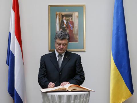 Ukraine's President Petro Poroshenko, standing under a framed photo of Dutch King Willem-Alexander and his wife Queen Maxima, signs a book of condolence as he commemorates victims of Malaysia Airlines Flight MH17 at the Dutch embassy in Kiev