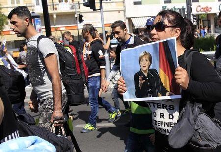 A woman holds a picture of German Chancellor Angela Merkel as migrants set off on foot for the border with Austria from Budapest, Hungary, September 4, 2015. PHOTO BY REUTERS/Bernadett Szabo