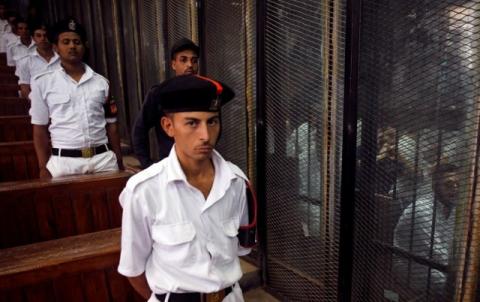 Police officers stand guard as defendants accused of involvement in the 2015 assassination of Egypt's top prosecutor sit in a cage in a courtroom, on the outskirts of Cairo, Egypt, June 17, 2017. PHOTO BY REUTERS/Amr Abdallah Dalsh