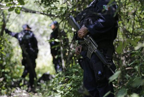 Iguala police officers stand guard at an area near clandestine graves at Pueblo Viejo, in the outskirts of Iguala, southern Mexican state of Guerrero