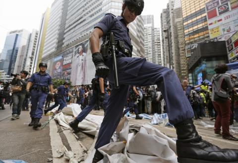 Police officers walk across obstacles during a clearance at the last "Occupy" protest site blocking a main road at Causeway Bay shopping district in Hong Kong, December 15, 2014. PHOTO BY REUTERS/Athit Perawongmetha