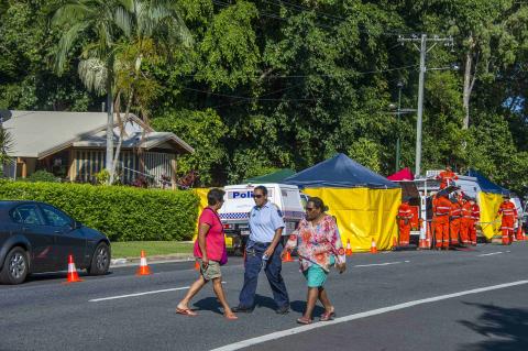 A police officer walks with locals outside the scene of a stabbing attack at a home (L) in Cairns, northern Queensland, December 19, 2014. PHOTO BY REUTERS/Stringer