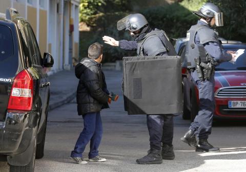 A French police officer speaks to a child outside a school as he secures the Castellane housing area in Marseille, February 9, 2015. PHOTO BY REUTERS/Jean-Paul Pelissier