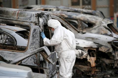 A French police officer inspects burned vehicles outside the Splendid Hotel in Ouagadougou, Burkina Faso, January 17, 2016. PHOTO BY REUTERS/Joe Penney