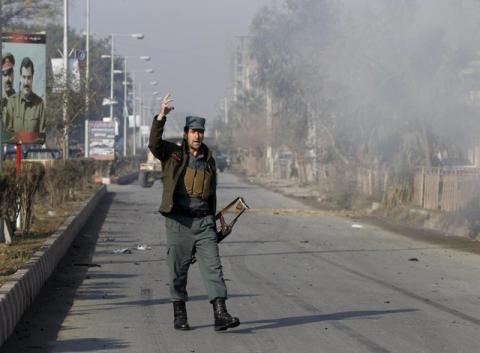 An Afghan policeman reacts as smoke billows during an attack near the Pakistani consulate in Jalalabad, Afghanistan, January 13, 2016. PHOTO BY REUTERS/ Parwiz