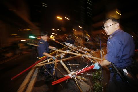 Policemen remove a barricade at a protest site in Mongkok shopping district in Hong Kong