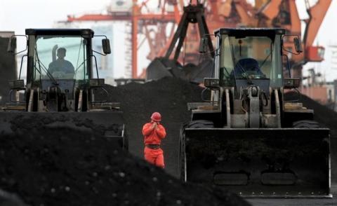 An employee walks between front-end loaders which are used to move coal imported from North Korea at Dandong port in the Chinese border city of Dandong, Liaoning province, December 7, 2010. PHOTO BY REUTERS/Stringer
