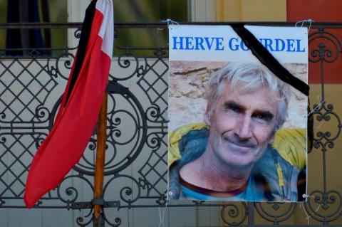 A portrait of mountain guide Frenchman Herve Gourdel hangs near a French flag outside the town hall in Saint-Martin-Vesubie, September 25, 2014. PHOTO BY REUTERS/Patrice Masante