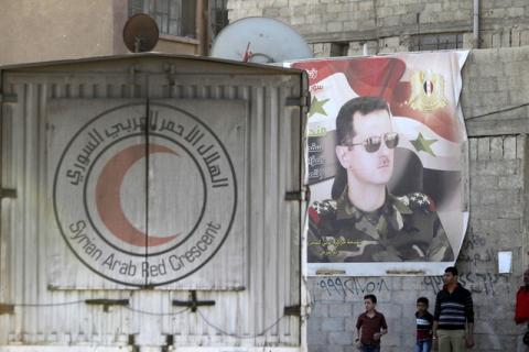 An aid convoy of the Syrian Arab Red Crescent enters the Wafideen Camp, which is controlled by Syrian government forces, near a poster of Syria's president Bashar al-Assad, to deliver aid into the rebel-held besieged Douma neighborhood of Damascus, Syria, March 4, 2016. PHOTO BY REUTERS/Omar Sanadiki