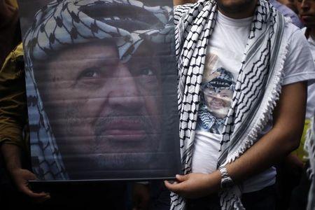 Palestinian Fatah supporters wear a T-shirt and hold a poster depicting late Palestinian leader Yasser Arafat during a rally marking the tenth anniversary of his death, at Al-Azhar University in Gaza City, November 11, 2014. PHOTO BY REUTERS/Suhaib Salem