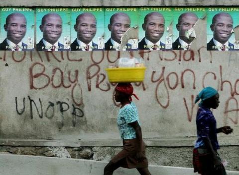 Haitians walk past posters of presidential candidate Guy Philippe at a street in Port-au-Prince, Haiti, February 3, 2006. PHOTO BY REUTERS/Eduardo Munoz