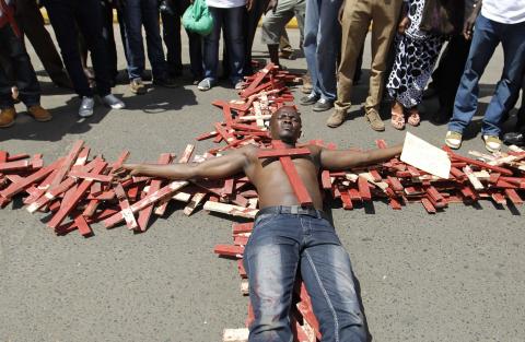 A protester lies on top of wooden crosses, symbolising people killed in a series of attacks, during the #OccupyHarambeeAve protest in Kenya's capital Nairobi, November 25, 2014. PHOTO BY REUTERS/Thomas Mukoya
