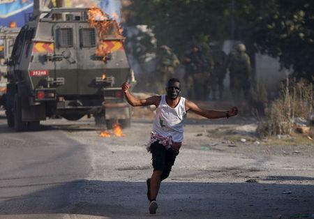 A Palestinian protester runs after throwing a molotov cocktail towards Israeli soldiers during clashes following the funeral of Palestinian youth Laith al-Khaldi, in Jalazoun refugee camp near the West Bank city of Ramallah August 1, 2015. PHOTO BY REUTERS/Mohamad Torokman