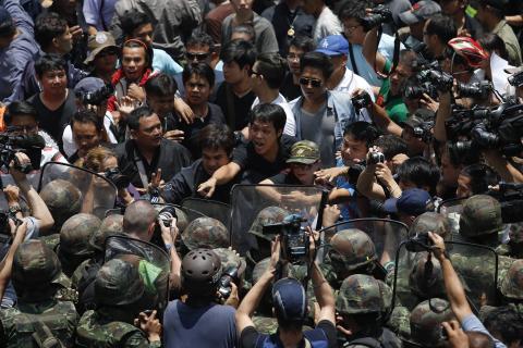 Protesters against military rule and soldiers deployed to control them confront each other at Bangkok's shopping district