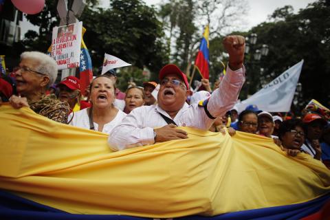 Elderly protesters carry a flag during a march for peace in downtown Caracas