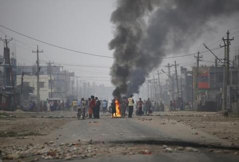 Protesters stand near burning tyres as they gather to block the highway connecting Nepal and India, during a general strike called by Madhesi protesters demonstrating against the new constitution in Birgunj, Nepal November 5, 2015. PHOTO BY REUTERS/Navesh Chitrakar