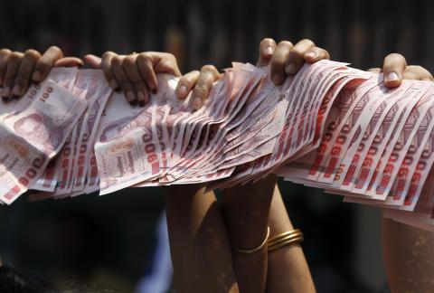 Anti-government protesters hold Thai baht banknotes to donate to protest leader Suthep Thaugsuban (unseen) as he leads a march through central Bangkok