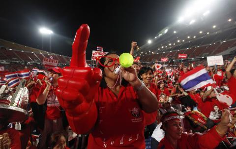 A red-shirted supporter gestures during a rally at Rajamangala national stadium in Bangkok
