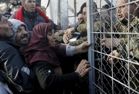 Syrian refugees struggle to enter Macedonia through a narrow border crossing as Macedonian policemen try to shut a metal gate near to the Greek village of Idomeni, December 4, 2015. PHOTO BY REUTERS/Yannis Behrakis