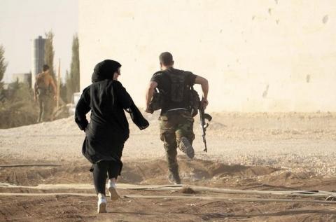 A woman reporter runs with a rebel fighter to avoid snipers at the frontline against the Islamic State fighters in Aleppo's northern countryside, October 10, 2014. PHOTO BY REUTERS/Jalal Al-Mamo