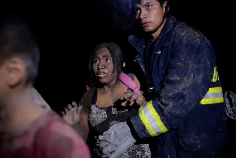 A rescue worker helps a woman covered with ash after Fuego volcano erupted violently in El Rodeo, Guatemala, June 3, 2018. PHOTO BY REUTERS/Fabricio Alonzo